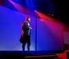 A person stands on stage beside a large screen displaying the American flag and the words Cherish  Defend Freedom