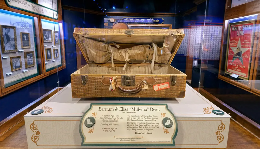 The image shows a worn historical suitcase displayed in a museum accompanied by informational text about Bertram and Eliza Millvina Dean Titanics youngest survivor