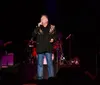 A man is passionately singing into a microphone on a colorful stage