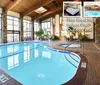 The image shows an inviting indoor pool area with wooden beams stone accents and lounge chairs featuring text about amenities like free breakfast an indoor pool and an outdoor pool