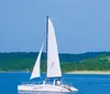 A group of people enjoys a sunny day sailing on a boat named Spirit of America with a backdrop of a lakeshore and buildings