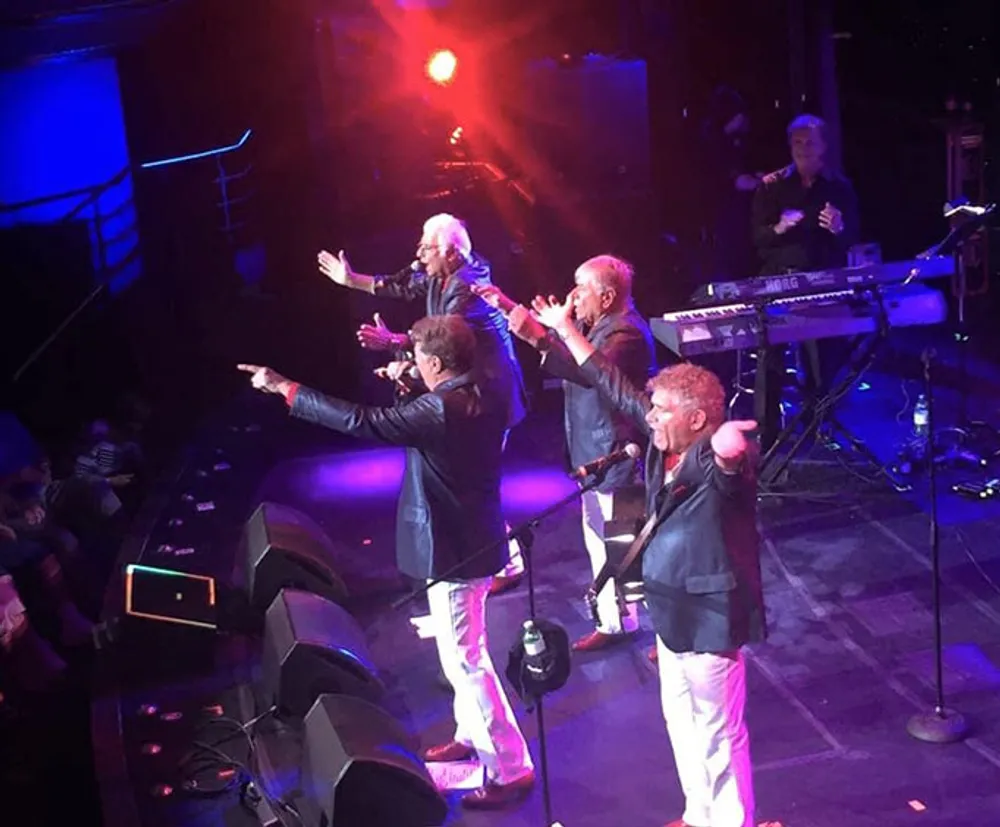 A group of performers is entertaining an audience on stage under vibrant stage lighting