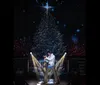 A person dressed as Santa Claus is energetically dancing on stage with a singer in a shiny gold jacket