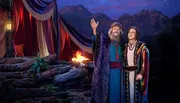 The image depicts two characters, likely from a biblical or historical setting, in colorful robes looking skyward with a campfire and dramatic mountainous landscape in the background.