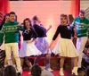 A group of people are performing on stage in festive holiday sweaters exuding a cheerful Christmas spirit