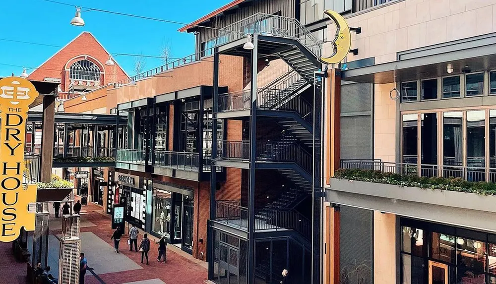 The image shows an urban outdoor shopping area with pedestrians stores like Sephora an external staircase and a quirky banana-shaped sign under a clear blue sky