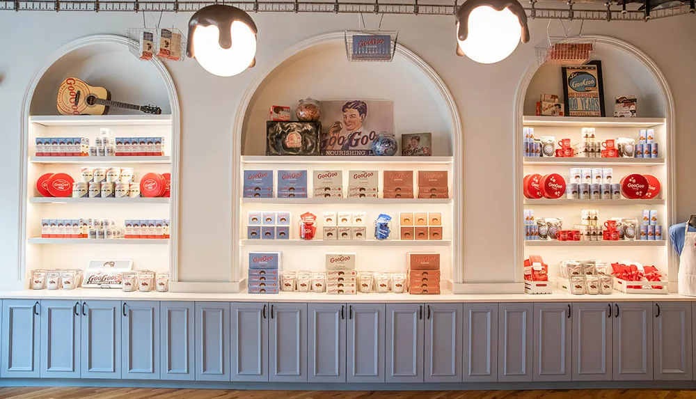 The image shows a bright and orderly display of Goo Goo branded confectionery and merchandise on shelves within arched alcoves suggesting a specialty shop or dedicated area within a store
