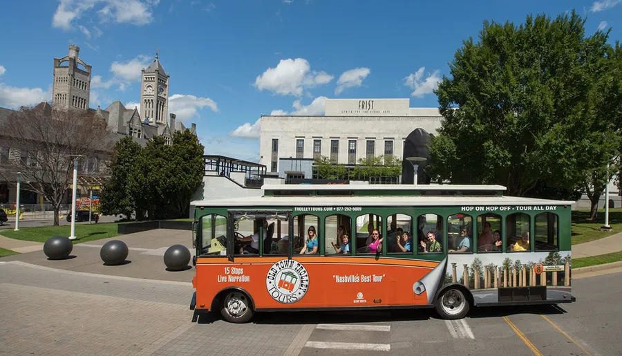 A trolley full of tourists is passing by the Frist Art Museum on a sunny day.