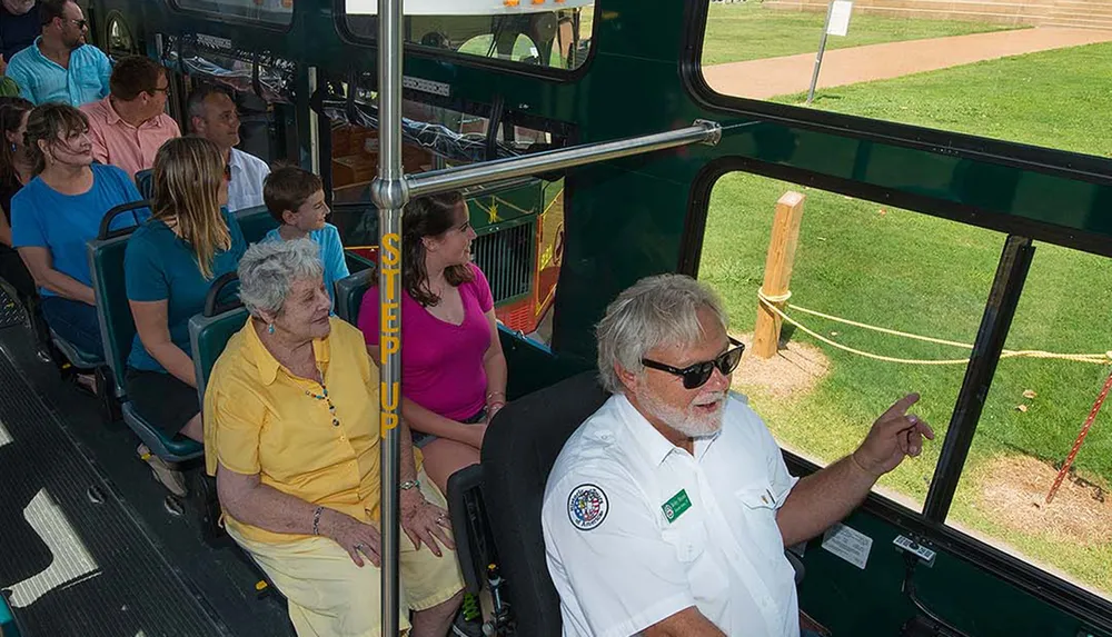 A group of passengers is seated on a trolley bus listening to a guide who appears to be providing information
