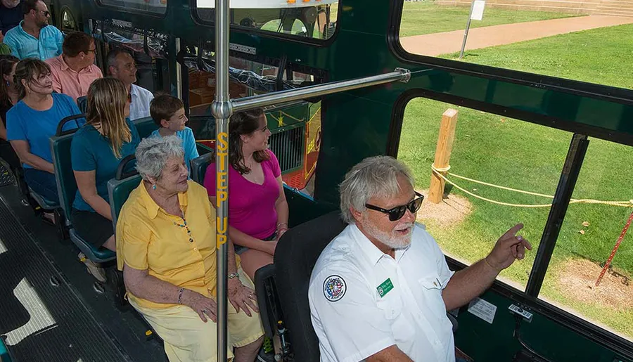 A group of passengers is seated on a trolley bus listening to a guide who appears to be providing information.