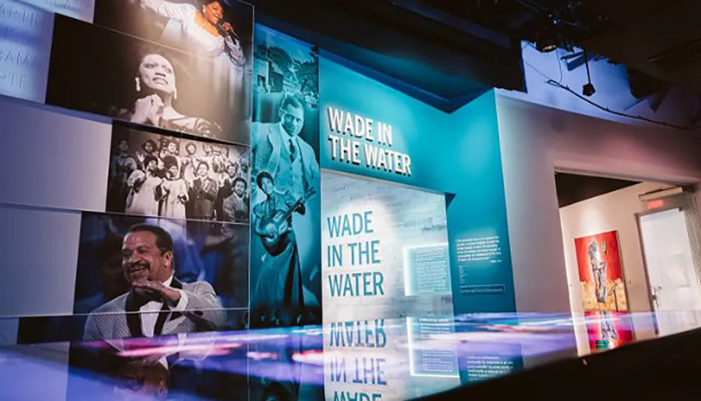 This image depicts an exhibition space with vibrant blue lighting and walls featuring historical photographs and text panels with a prominent display titled Wade in the Water