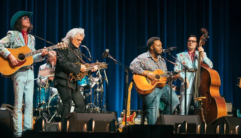 Four musicians including a guitarist a mandolin player a vocalist with an acoustic guitar and a double bassist are performing live on stage