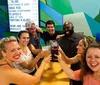 A group of cheerful people are toasting with drinks in a lively bar setting