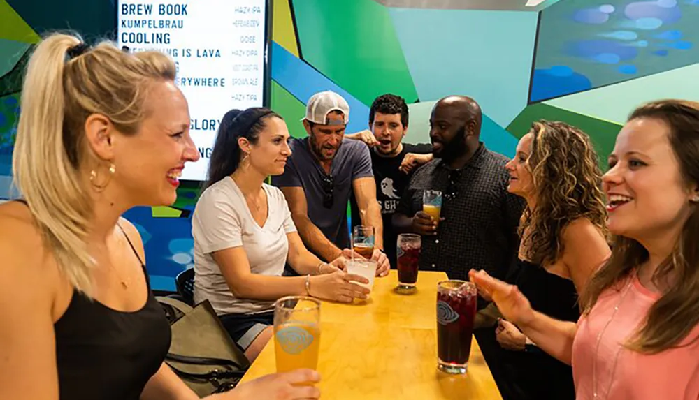 A group of people are engaged in what appears to be a lively and enjoyable conversation at a bar with various beverages in hand