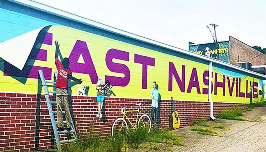 People are painting a colorful mural that says EAST NASHVILLE on the side of a building.