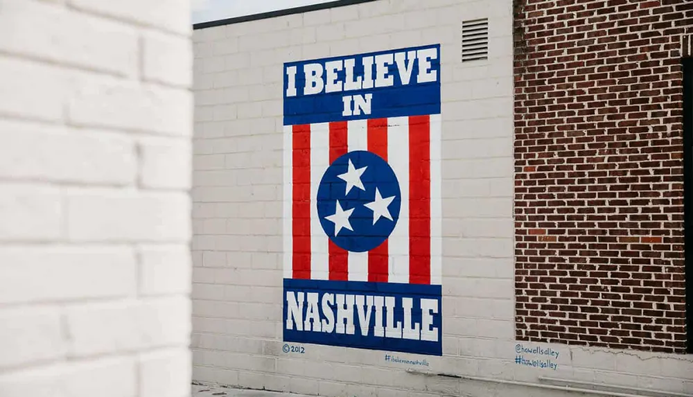 The image shows a mural on a brick wall with the phrase I BELIEVE IN NASHVILLE featuring red and white stripes and a central circle containing three stars on a blue background