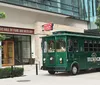 A trolley-style bus marked Music City BrewHop is parked in front of a building with classical Greek architecture