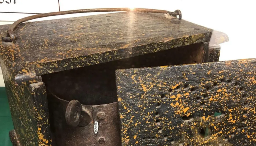 The image shows a weathered and rusted metal object with flaking yellow paint, possibly a piece of industrial or agricultural equipment.