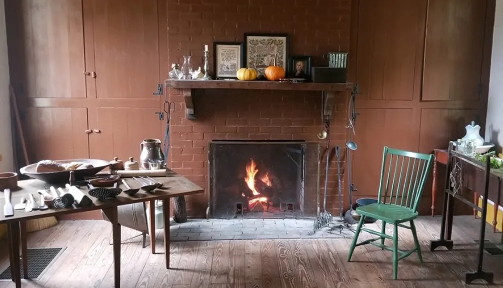 A cozy room with a lit fireplace wooden furniture and various items on tables and the mantelpiece