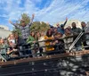 A lively group of people is smiling and posing for a photo with drinks in their hands on a bustling city street lined with bars and shops