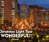 The image captures a dusk view of a city street lined with illuminated buildings decorative lights and a statue all framed by festive garland in the foreground