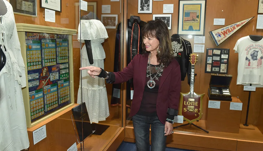 A person is pointing at something in a display case at a museum exhibition with various memorabilia
