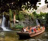 Tourists enjoy a boat ride in an enclosed space with lush vegetation and a waterfall in the background