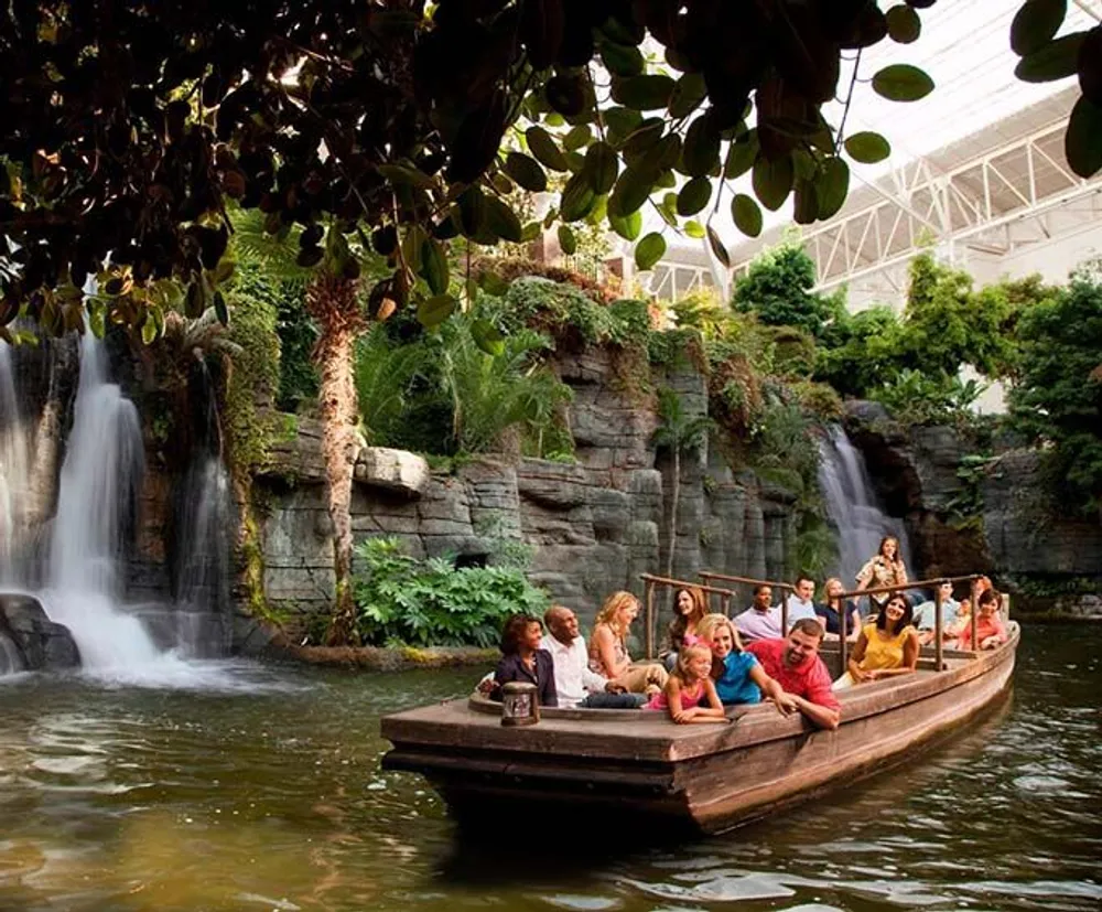 Tourists enjoy a boat ride in an enclosed space with lush vegetation and a waterfall in the background