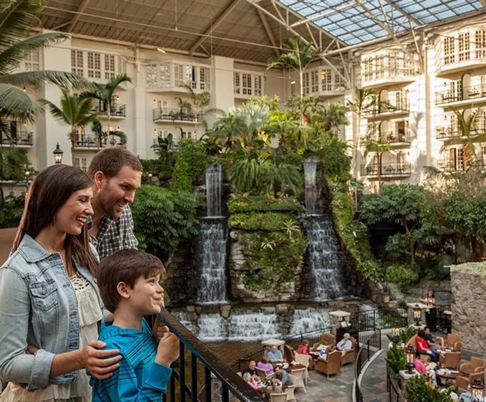 A family is enjoying a view of a lush indoor atrium with waterfalls and seating areas