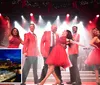 A group of performers in matching red outfits are joyfully singing and dancing on a festively-lit stage