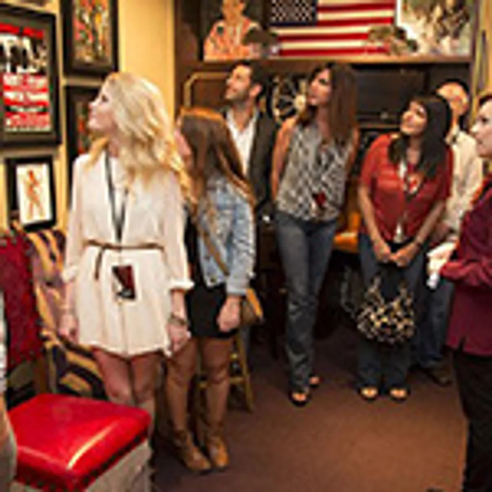 A group of people is attentively looking at something off-camera in a room decorated with posters and an American flag