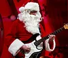 A person dressed as Santa Claus plays an electric guitar on stage during the Opry Country Christmas event