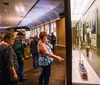 A group of people is smiling and looking at exhibits possibly within a museum or gallery where a guitar is displayed under glass