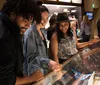 A group of people is smiling and looking at exhibits possibly within a museum or gallery where a guitar is displayed under glass