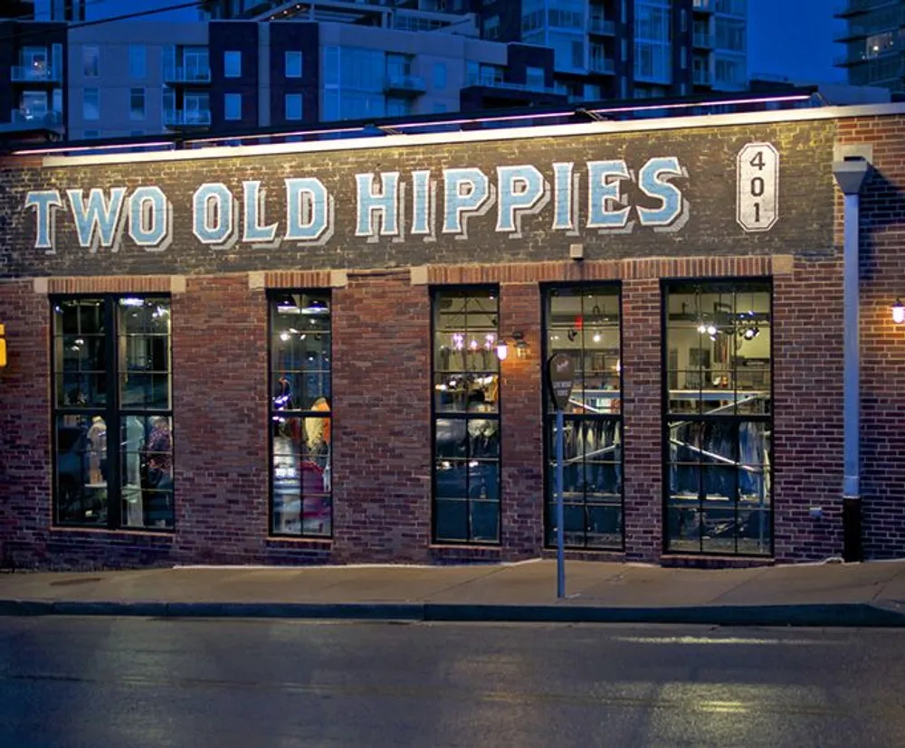 The image shows the exterior of a brick building at dusk with a lighted sign reading TWO OLD HIPPIES above the entrance