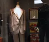 The image shows a display case with various music memorabilia including a decorative guitar photographs clothing a cowboy hat and hand-written notes suggesting a tribute to a musicians career