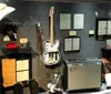 The image shows a display case with various music memorabilia including a decorative guitar photographs clothing a cowboy hat and hand-written notes suggesting a tribute to a musicians career