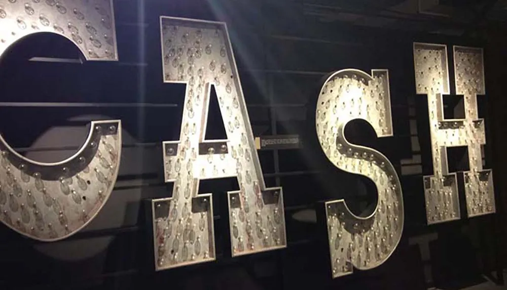 The image shows an illuminated sign with the word CASH where the letters are styled with decorative light bulbs