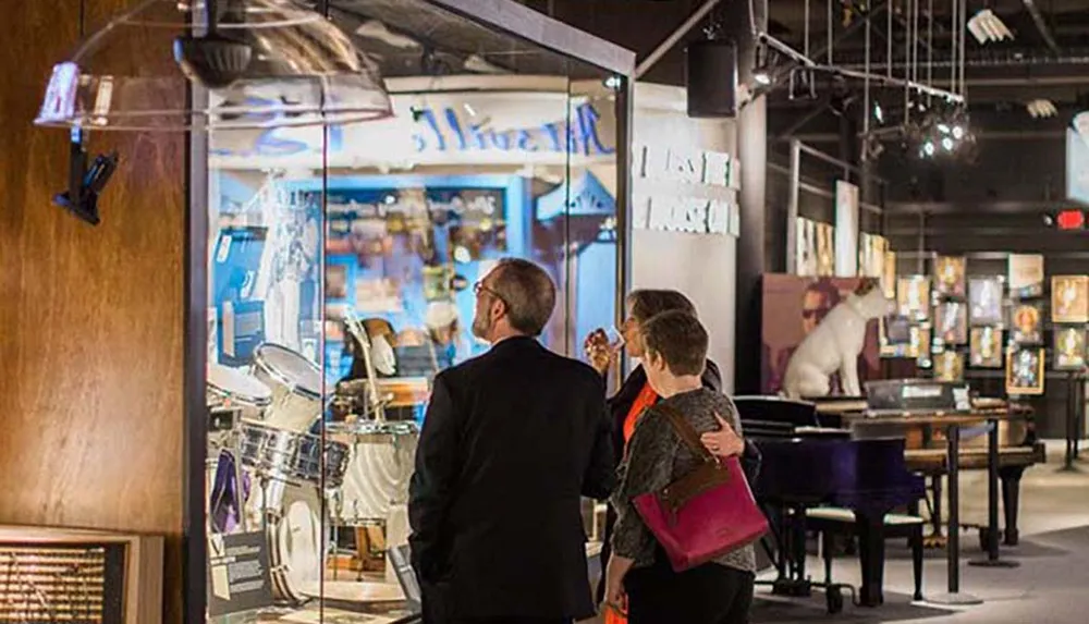 Two individuals observe exhibits inside a museum adorned with a variety of musical artifacts and displays