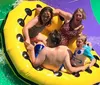 A group of friends is laughing and enjoying a sunlit ride down a water slide in a yellow raft