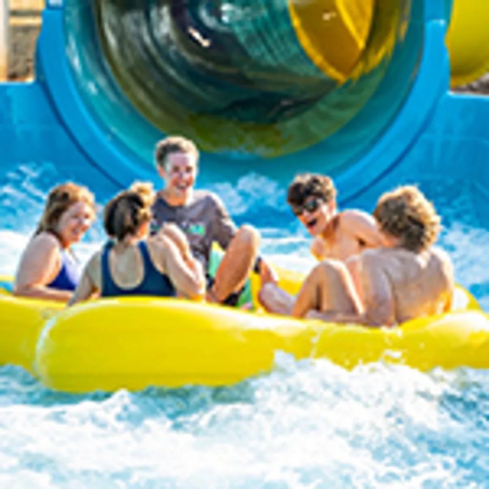 A group of people are enjoying a ride on a yellow inflatable raft down a water slide