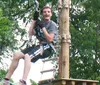 A person is gleefully zip-lining above a forested area