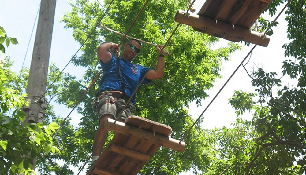 A person is traversing a high ropes course among the trees