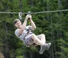 A person is gleefully zip-lining above a forested area