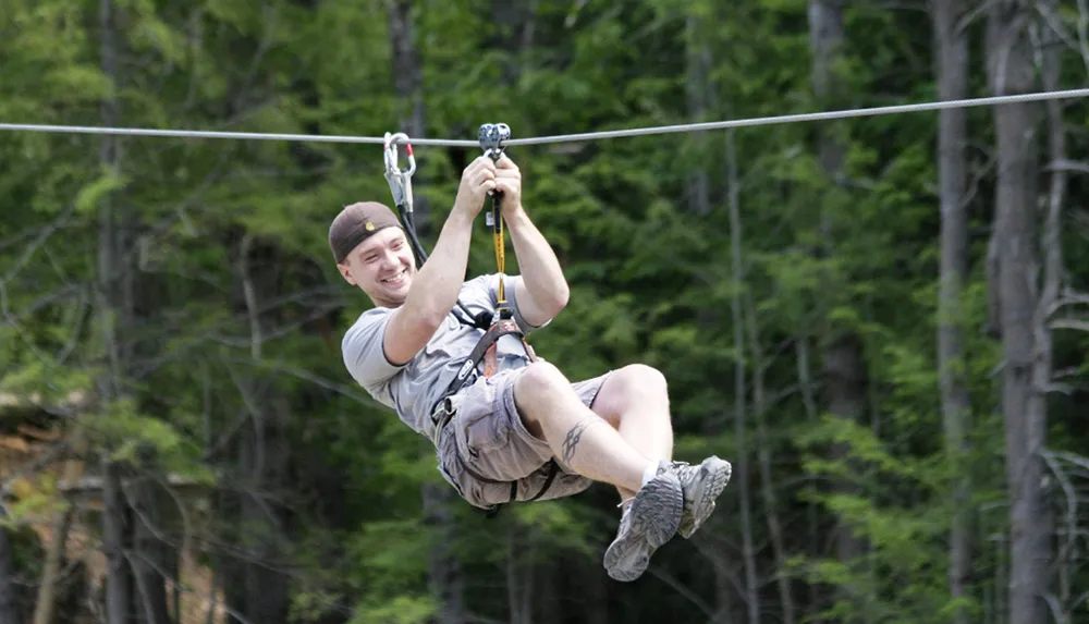A person is gleefully zip-lining above a forested area