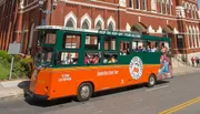 A green and orange trolley bus labeled 