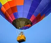 A colorful hot air balloon with a yellow basket is floating against a clear blue sky