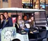 A group of people is enjoying a tour on a unique golf cart-like vehicle labeled JOYRIDE on a vibrant city street