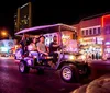 A group of people is enjoying a tour on a unique golf cart-like vehicle labeled JOYRIDE on a vibrant city street