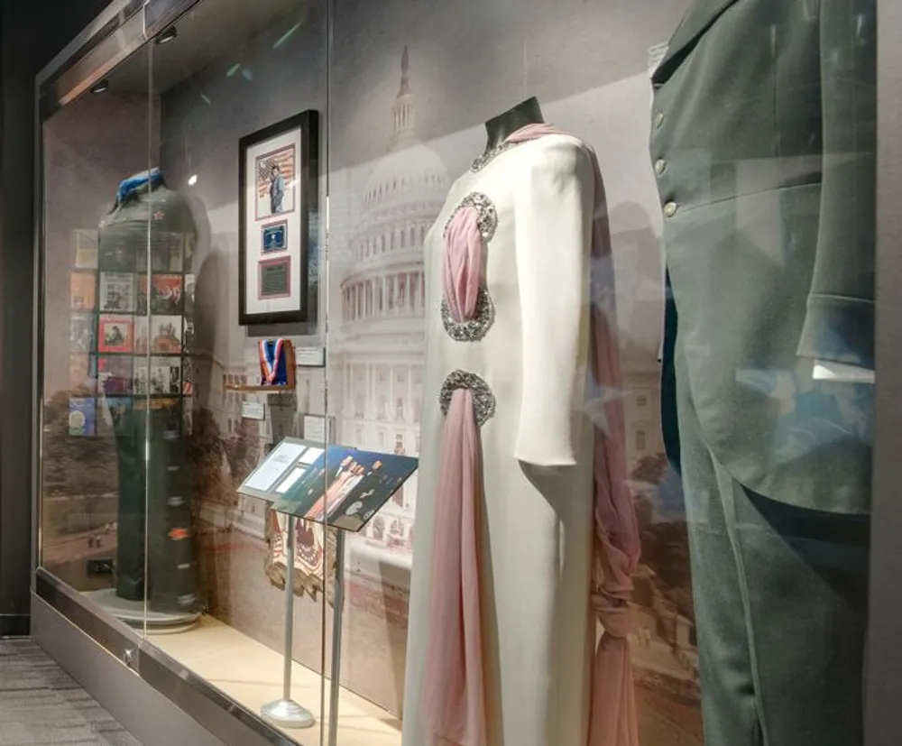 The image shows a museum display case containing historic ceremonial clothing and memorabilia possibly from significant political figures or events